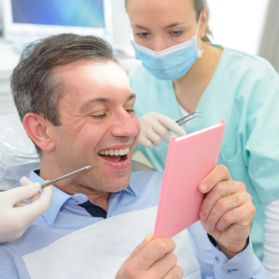 A man looking at his new dental crown in the mirror