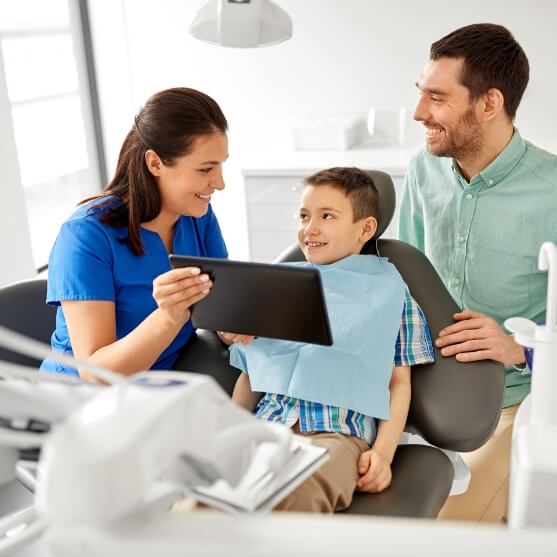 Father and child talking to dentist in dental treatment room