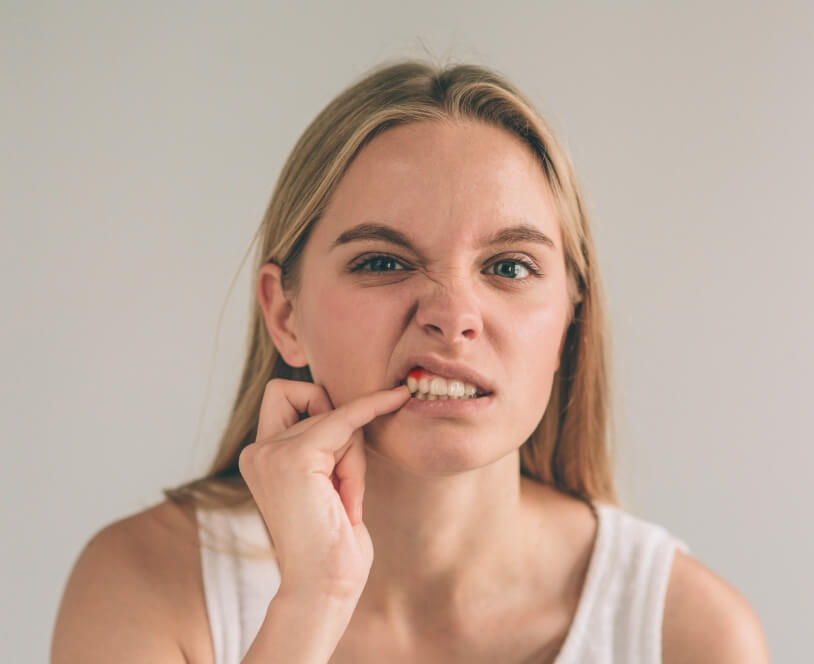 Woman in need of periodontal disease treatment pointing to inflamed gum tissue