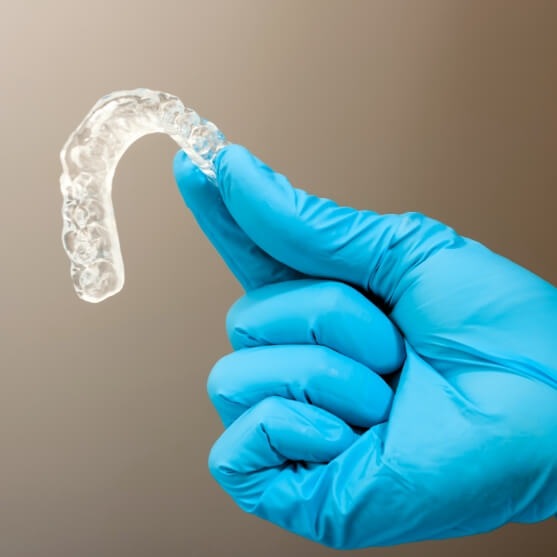 Hand holding a clear nightguard for bruxism