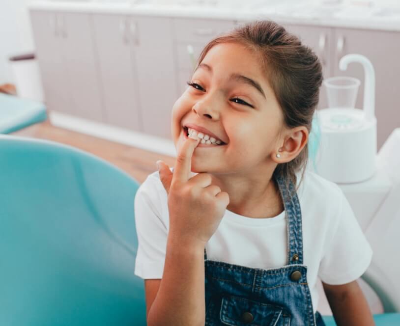 Young dental patient pointing to smile during children's dentistry visit