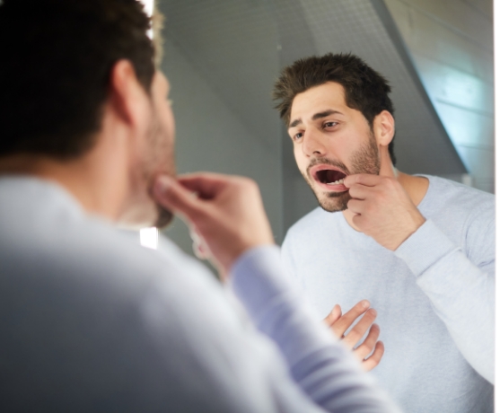 Man looking at smile before emergency dentistry visit