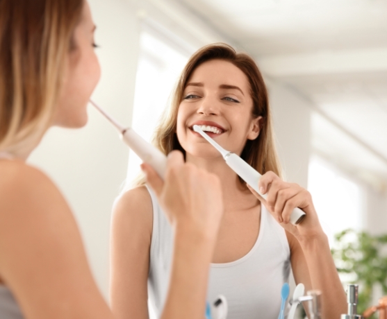 Woman brushing teeth to prevent dental emergencies
