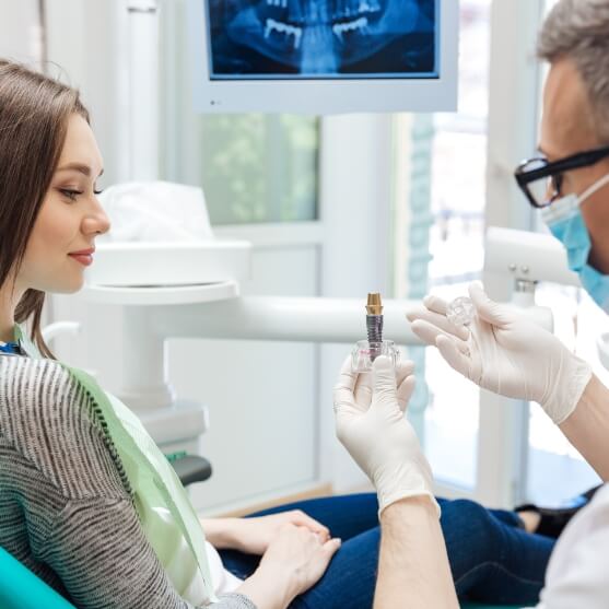 Dentist and patient looking at dnetal implant model