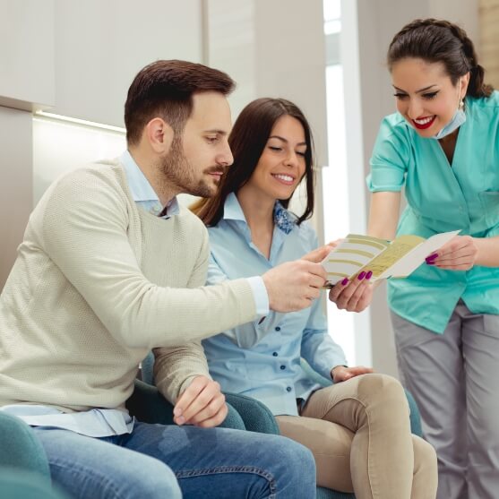 Dental team member and patients discussing what dental insurance covers