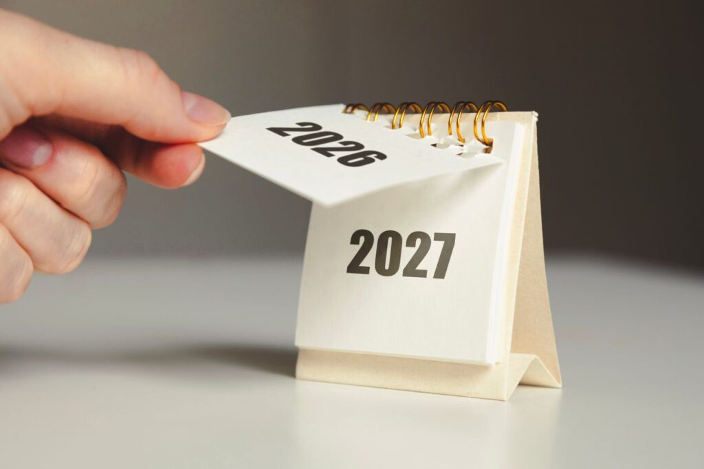 A hand changing a calendar from 2026 to 2027